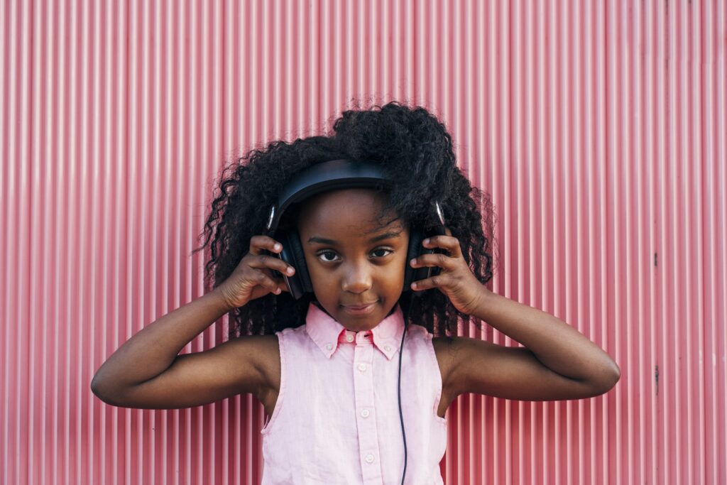 Happy kid girl listening to music and smiling. Childhood outdoors