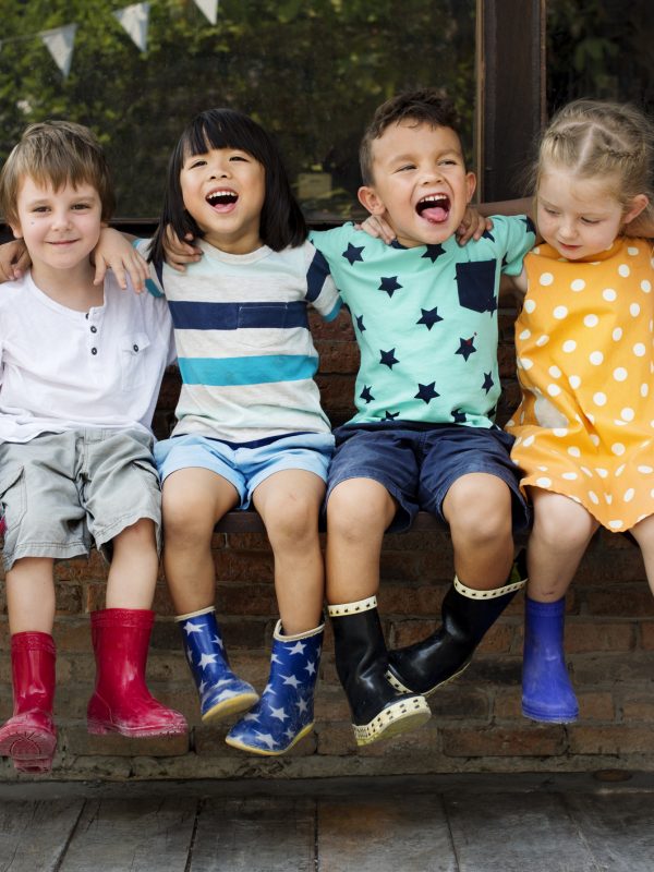 Kindergarten kids friends arm around sitting smiling